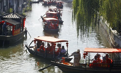 Wooden riverboats carrying wedding groups glide along a waterway in Fengjing town. Photo: Yang Hui/GT