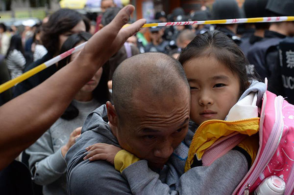 A man takes her daughter out of Mingtong Primary School in Kunming city, Yunnan province, September 26, 2014. A stampede left six pupils dead and 26 injured at the school on Friday. [Photo/Xinhua]