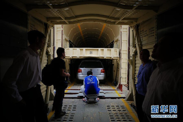 Workers load a car onto a Beijing-Hangzhou freight train on Sunday, September 28, 2014. The train is specially arranged by the Beijing Railway Administration for those who want to have a self-drive National Day holiday. With the service, passengers on rail lines linking Beijing and Hangzhou can reach destinations simultaneously with their cars transported by the specific freight train. Over 50 cars will be transported during the upcoming golden week holiday under the service, said the Beijing Railway Administration. [Photo/Xinhua]