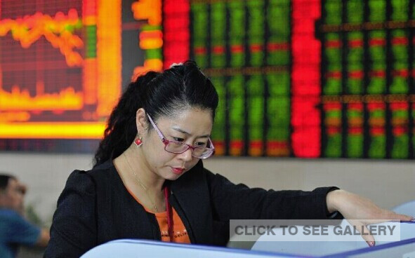 An investor reads stock information at a trading hall of a securities firm in Fuyang City, east China's Anhui Province, Sept. 16, 2014. (Xinhua/Lu Qijian)