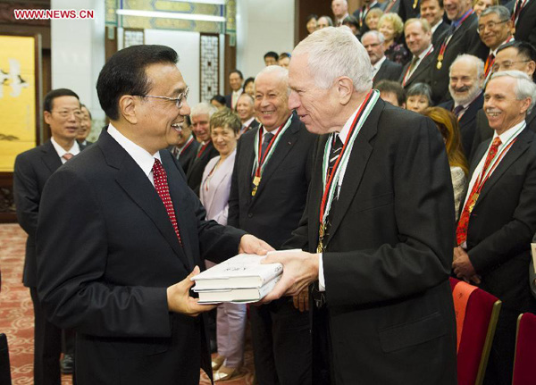 Chinese Premier Li Keqiang (L front) receives the book Mass Flourishing from the author, American economist Edmund Phelps (R front), in Beijing, China, Sept. 30, 2014. Li met with foreign experts and their families who were awarded China's 2014 Friendship Award for their contribution to the country's development here on Tuesday. (Xinhua/Huang Jingwen)