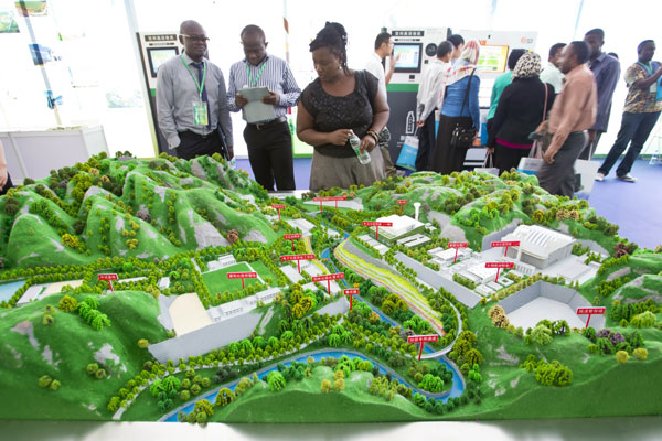 Tourists study the model of Lujiashan recycling base at an exhibition in Beijing on June 8. [Photo by Zhao Bing/For China Daily]