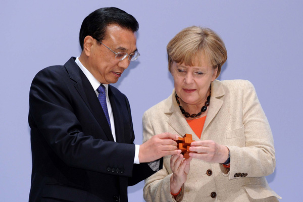 Premier Li Keqiang (left) gives a Luban Lock as a gift to German Chancellor Angela Merkel at the China-Germany Economic and Technological Forum during his visit to Berlin on Oct 10, 2014. [Photo/english.gov.cn]