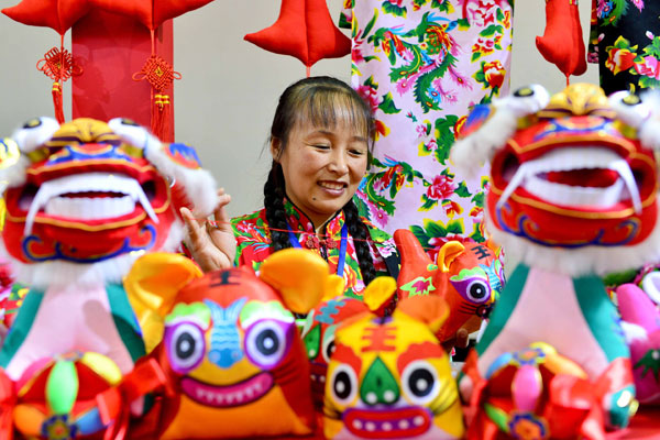 A woman from Shandong province shows traditional cloth toys.  [Photo by Wang Kaihao/China Daily]  