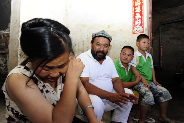 A mother weeps in gratitude as Alimjan Halik (second left) visits her family and donates money to her children in Bijie, Guizhou province. XIE QIANG/CHINA DAILY
