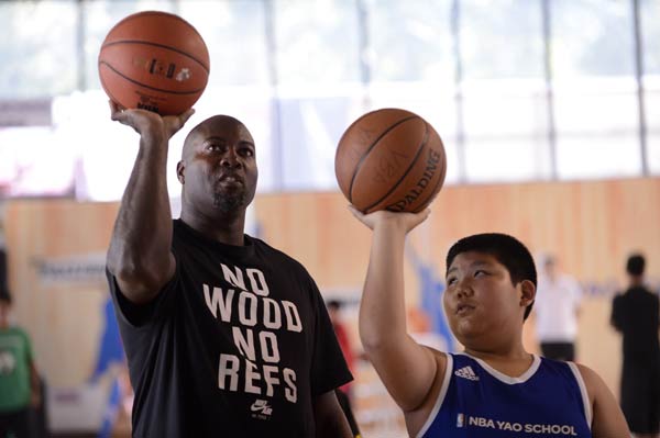Retired NBA allstar player Glen Rice shows a Chinese youngster how to shoot during a visit to the NBA Yao School in Beijing in September. WEI XIAOHAO / CHINA DAILY 