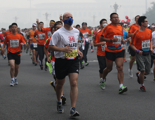 Some runners wear masks to protect themselves from heavy smog as they take part in the Beijing Marathon on Sunday.Wang Zhuangfei / China Daily   