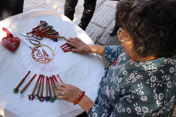 A local woman demonstrates her embroidery skills.[Photo by Wang Kaihao/China Daily]