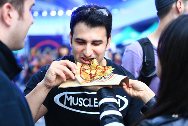 A man takes a bite of a slice of pizza at The Beijinger 2014 Pizza Cup Launch Party in Beijing on Oct 18, 2014. [Photo provided to chinadaily.com.cn]