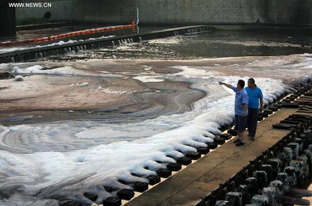 Working staff check the crude oil spills at the exit of the urban sewage pipeline network after a crude oil spill from a pipeline of PetroChina, the country's largest oil and gas producer, caused a huge fire in Dalian, a coastal city in northeast China's Liaoning Province, July 1, 2014. [Photo: Xinhua]