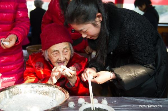 Huang Jingwen (L), a centenarian, makes traditional snack Yuanxiao with staff members of local community in Hefei, capital of east China's Anhui Province, Feb. 11, 2014, to celebrate the upcoming lantern festival which falls on Feb. 14 this year. Yuanxiao, or glutinous rice flour dumpling with sweetened stuffing, is a traditional food for the Lantern Festival.