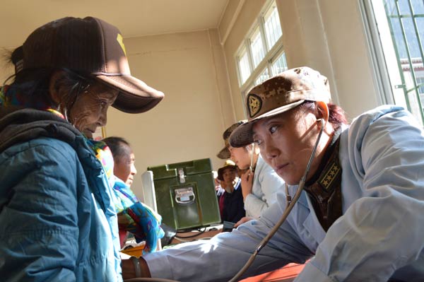 Military doctor Cui Shuhua (right) checks a local resident in Zhamo on Tuesday. Because of the poverty in the area, a special fund was set up to cover needy people's medical expenses.  Wang Xu / China Daily