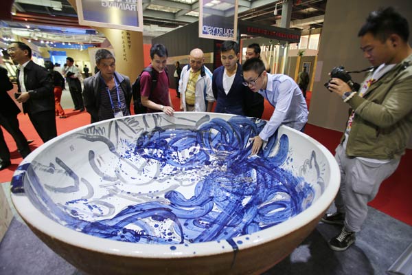 Visitors to the 2014 China Jingdezhen International Ceramic Fair check a giant bowl in Jingdezhen, Jiangxi province. The city is known as the capital of porcelain in China.  Zhu Wenbiao / For China Daily