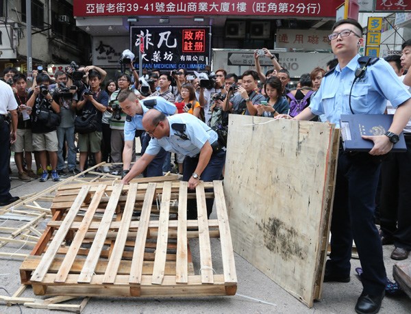 Police officers clean up barricades that had been blocking main roads in the Mong Kok district of Hong Kong on Thursday. EDMOND TANG/CHINA DAILY  
