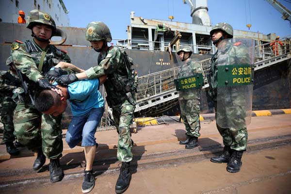 Border police arrest a smuggler during a anti-smuggling drill in Qingdao, East China's Shandong province, Sept 25, 2014. [Photo/Xinhua]  