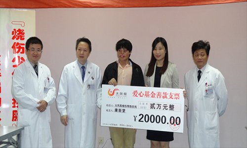 Kang Xinwang (middle) receives a donation from the Fire Phoenix charity. Photo: Yang Lan/GT