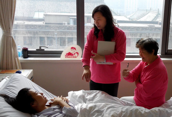 A volunteer (center) from an organization that provides advice for women with breast cancer talks with a patient after surgery in a Beijing hospital. Zou Hong / China Daily