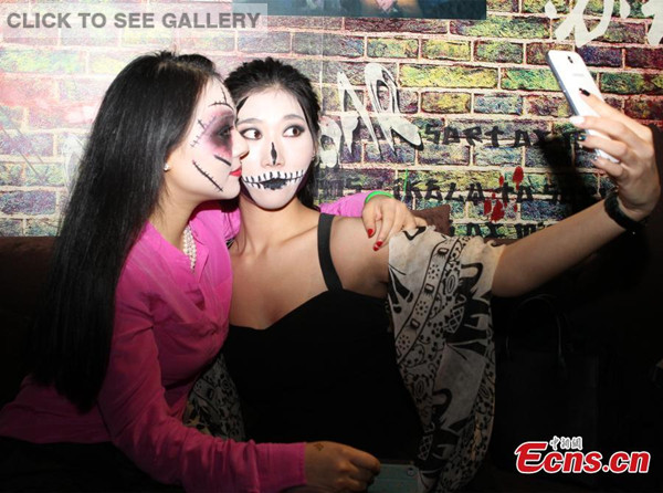 Young women wearing scary make-up pose for selfie at a Halloween party in Chongqing on October 30, 2014. [Photo: China News Service / Zhou Yi] 