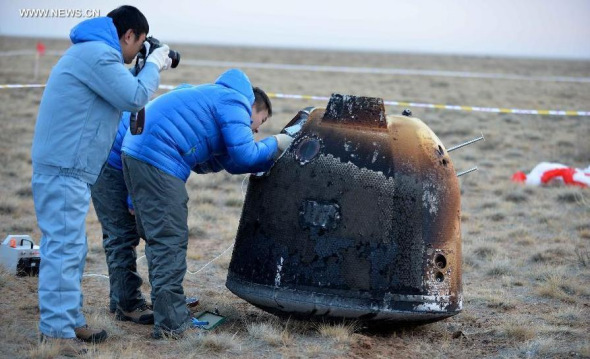 Researchers retrieve the return capsule of China's unmanned lunar orbiter in the central region of north China's Inner Mongolia Autonomous Region, Nov 1, 2014.(Xinhua/Ren Junchuan)  