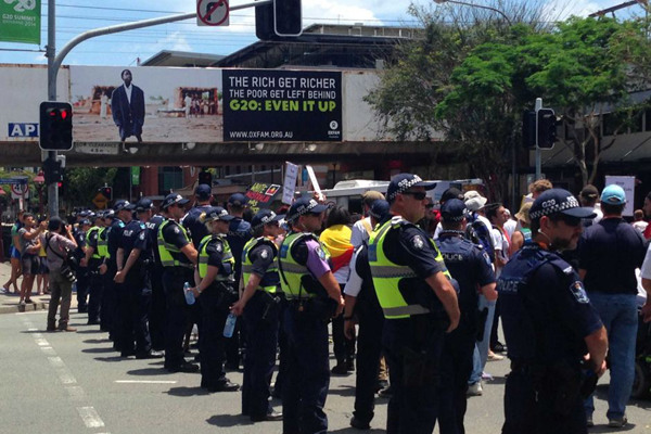Police line the streets of South Bank as a protest crosses the street in Brisbane. (612 ABC Brisbane: Amanda Dell) 