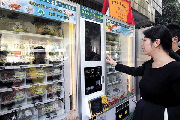 A resident checks out a grocery vending machine Friday in Jingan District. This is the first of 200 machines dispensing meat, fish, eggs, fruit and fresh veg planned over the next year in Shanghai. - Dong Jun