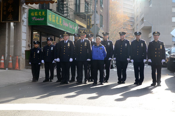 New York Police Department Transit Bureau Chief Joseph Fox (foreground center) stands with other transit officers in tribute to WaiKuen Kwok, who was fatally pushed in front of a subway train on Nov 16, as his coffin is carried out of a Chinatown funeral parlor on Sunday. Fox is flanked by Det. Sue Too, Asian community liaison for the New Immigrant Outreach Unit of the NYPD Community Affairs Bureau, and Vincent Coogan,Transit Bureau assistant chief. Lu Huiquan / For China Daily
