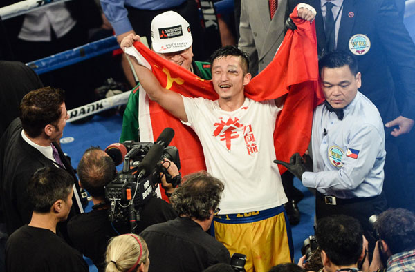 Zou Shiming of China celebrates his victory over Kwanpichit Onesongchaigym of Thailand during their World Boxing Organisation (WBO) 12-round welterweight title fight at the Venetian Macao hotel in Macao November 23, 2014.[Photo/Xinhua]