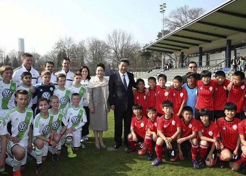 Chinese President Xi Jinping and his wife Peng Liyuan pose for a photo with youth players from China and Germany in Berlin, March 29, 2014. [Photo: Xinhua]