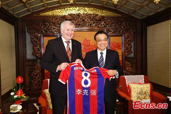 Chinese Premier Li Keqiang (R) receives a jersey of the German football team Bayern Munich as a gift from visiting governor of the German state of Bavaria Horst Seehofer in Beijing on Monday, November 24, 2014. Li expressed Chinas hope to strengthen sports industry cooperation with Germany during his meeting with the visiting governor. [Photo: China News Service/ Peng Jiansheng] 