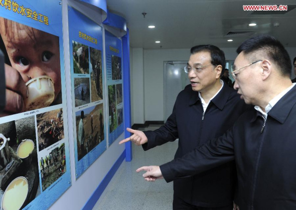 Chinese Premier Li Keqiang views a poster of rural drinking water safety project during his visit to the Ministry of Water Resources in Beijing, capital of China, Nov. 24, 2014. Li Keqiang made an inspection tour of the Ministry of Water Resources in Beijing on Monday. (Xinhua/Zhang Duo)