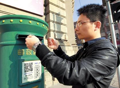 A man uses a postbox printed with a QR code for the courier service.  Xinhua