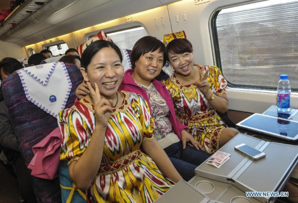 Passengers Sun Zhenzhen (L) from central China's Hubei province and Liu Xueqin (R) from Urumqi pose for photo on the CRH train D8602 which heads to Hami from Urumqi, capital of northwest China's Xinjiang Uygur Autonomous Region, Nov 16, 2014. (Xinhua/Zhao Ge) 