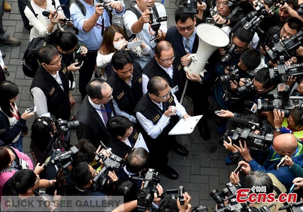 Reporters crowd round a bailiff (C) who reads out the injunction and enforcement order outside the Citic Tower in Admiralty, Hong Kong on Nov 18, 2014. [Photo: China News Service / Zhang Yu] 