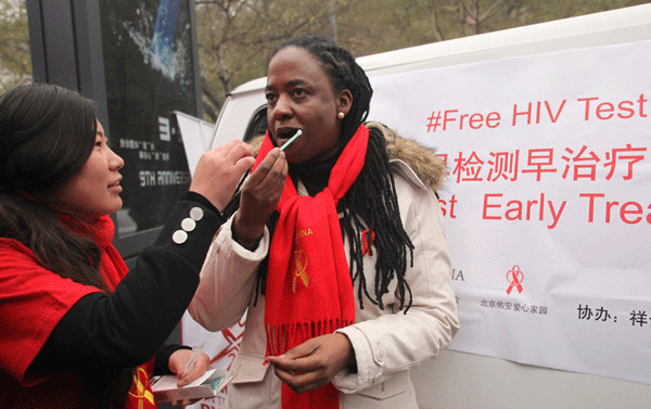 Catherine Sozi, UNAIDS country director of China, takes a rapid test for HIV/AIDS on Saturday in Beijing during a campaign to mark World Aids Day, which falls on Dec 1 every year. Volunteers also provide information and tools to fight the disease. Zou Hong / China Daily