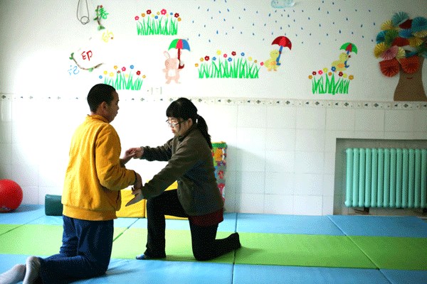 Xu Yulu, a teacher at the Disabled Person's Rehabilitation Center in Beijing, interacts with a mentally disabled man. China is working with NGOs to educate disabled youngsters and their parents to provide a better understanding of the relationship between sexuality and their physical and mental conditions. Wang Jing / China Daily