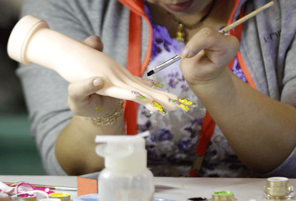 A physically disabled person uses a brush to manicure a model hand during a competition for people with disabilities in Nanjing, Jiangsu province on Sept 14.