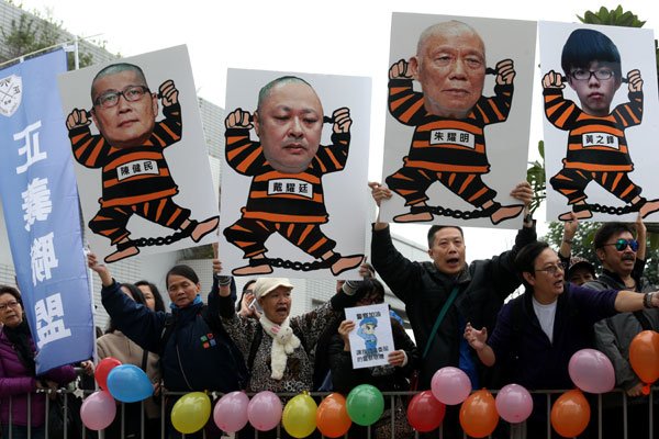 Protest opponents carry caricatures of (from left) Chan Kin-man, Benny Tai, Chu Yiu-ming and student leader Joshua Wong outside Central Police Station in Hong Kong on Wednesday before Tai, Chan and Chu surrendered themselves to police. EDMOND TANG / CHINA DAILY 