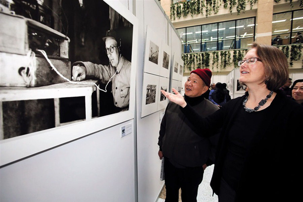 Susan Lawrence, granddaughter of Briton Michael Lindsay, shows visitors a picture of her grandfather yesterday during a photo show at Shanghai Library. More than 200 photos Lindsay took in China during 1937-45 are exhibited in town. -Zhang Suoqing