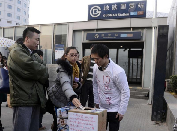 Passers-by give money to Xia outside a subway station in Beijing on Nov 29, 2014.