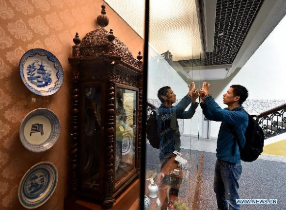 A visitor takes photos of exhibits through a window at the Macao Museum in south China's Macao, Dec. 10, 2014. Macao, covering a total area of more than 30 square kilometers, has more than 20 museums, which is a very high density in the world, according to Ung Vai Meng, president of the Cultural Affairs Bureau of Macao Special Administrative Region. (Xinhua/Li Xin)