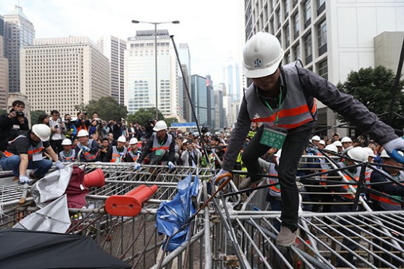 Workers remove barricades at an area blocked by protesters near the government headquarters building at the financial Central district in Hong Kong, December 11, 2014. [Photo by Roy Liu/Asianewsphoto]