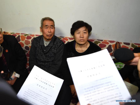Li Sanren (L) and Shang Aiyun, parents of Huugjilt who was executed in a controversial 1996 rape and murder case, receive legal document on retrial in Hohhot, capital of north China's Inner Mongolia Autonomous Region, Dec. 15, 2014. (Xinhua/Ren Junchuan)