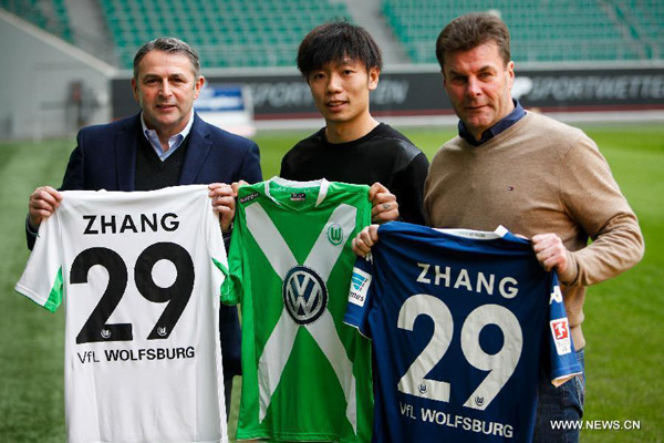 Zhang Xizhe (C) of China, Wolfsburg's head coach Dieter Hecking (R) and Wolfsburg' s manager Klaus Allofs display Zhang Xizhe's jerseys after a press conference in Wolfsburg, Germany, on Dec 16, 2014. German Bundesliga's VfL Wolfsburg announced the signing of Chinese midfielder Zhang Xizhe on Tuesday in Wolfsburg. (Xinhua/Zhang Fan) 