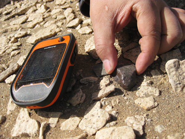 A meteorite hunter uses GPS to fix the location of an object his team discovered in Lop Nur, Xinjiang. [Photo by Zhao Yuxian / for China Daily]  