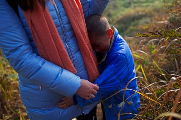 Kun Kun hugs a journalist who came to interview the 8-year-old boy, whose village launched a petition to drive him out of the village in Sichuan province for fear of HIV/AIDS.CHEN JIE / FOR CHINA DAILY 