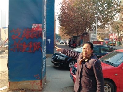 A woman points to red graffiti that said AIDS demolition team in Nanyang, Henan province, Dec 23, 2014. [Photo/the Beijing News]