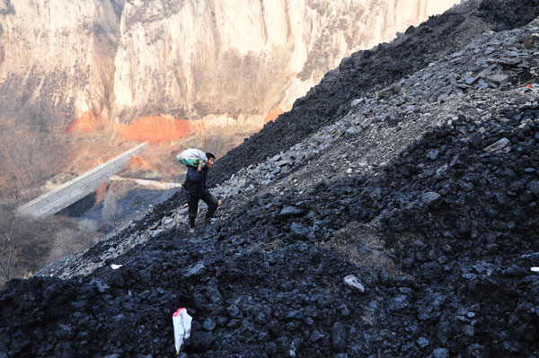 A villager in Zhongyang county, Shanxi province, picks up and carries away mineral waste from a nearby coal mine for his own use in November. CHINA DAILY  