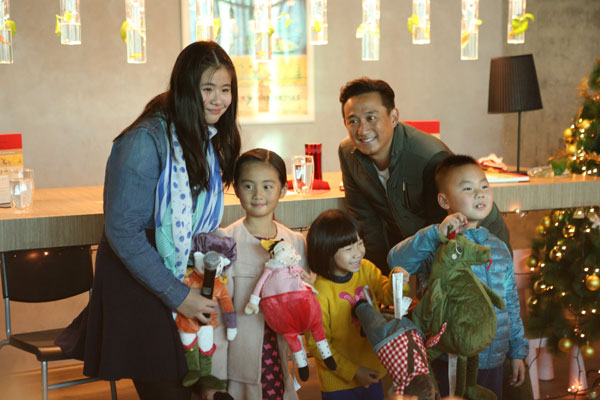 Linda Liu (left), Christine Huang (second left) and her father, actor Huang Lei, with young fans at the book-release party in Beijing on Dec 21. [Photo/China Daily]  