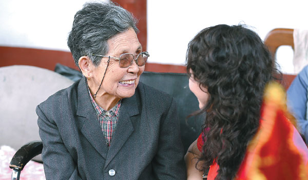 A volunteer chats with an elderly resident at a nursing home in Beijing. Wing Zhen / for China Daily  
