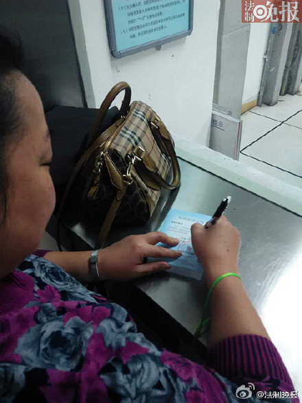 A passenger writes a note at a subway station to clear herself out of responsibility for getting late to work after a glitch delayed several trains in Beijing, Dec 26, 2014. [Photo from Legal Evening News' Sina Weibo post]  